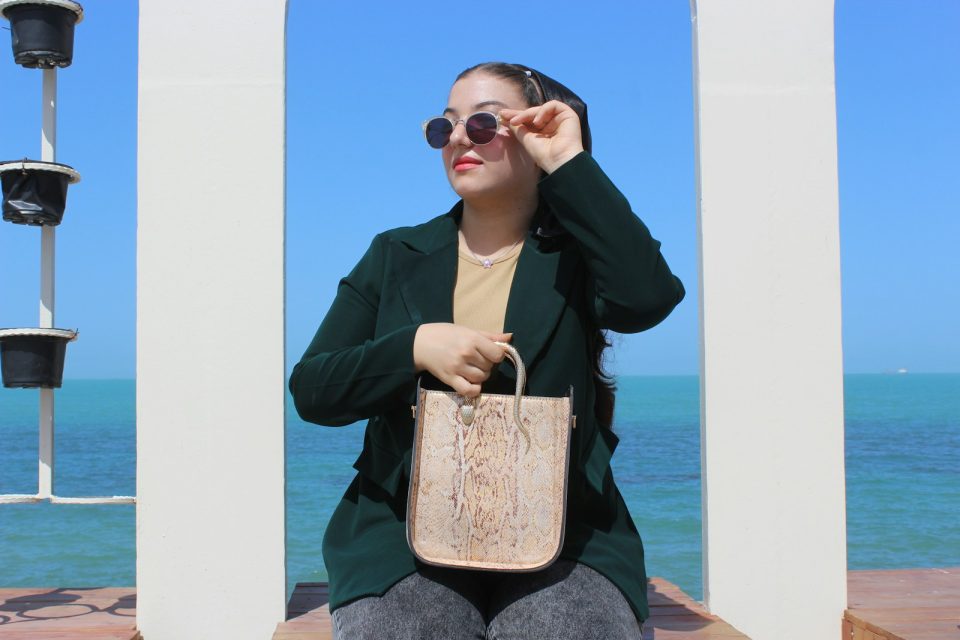 Woman in sunglasses holds a patterned tote bag.